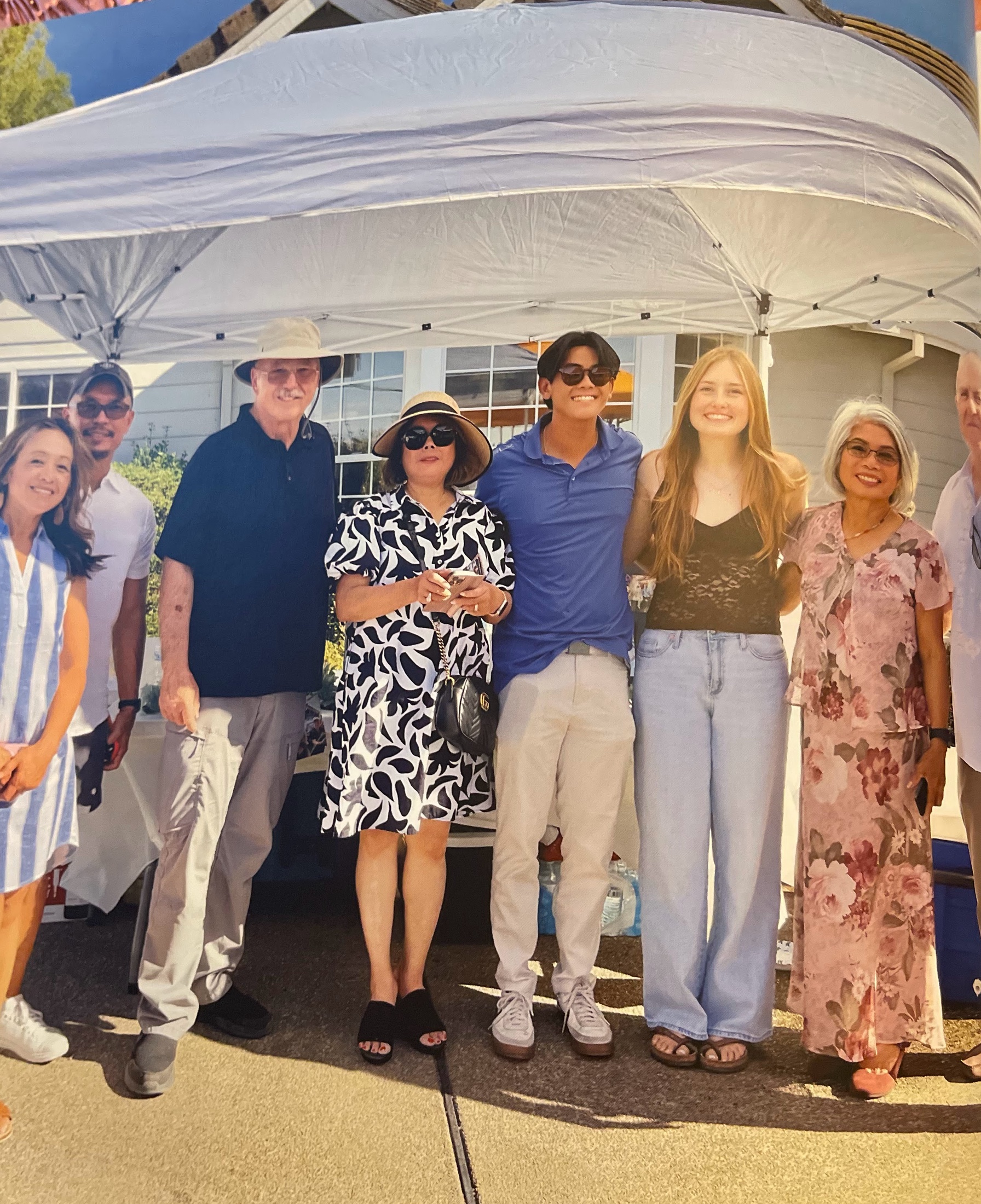 A group of smiling guests gathered beneath a canopy